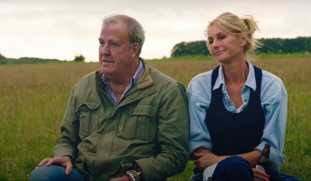 Cast of Clarkson's Farm season 3 showing Jeremy Clarkson sitting with his girlfriend Lisa in the field